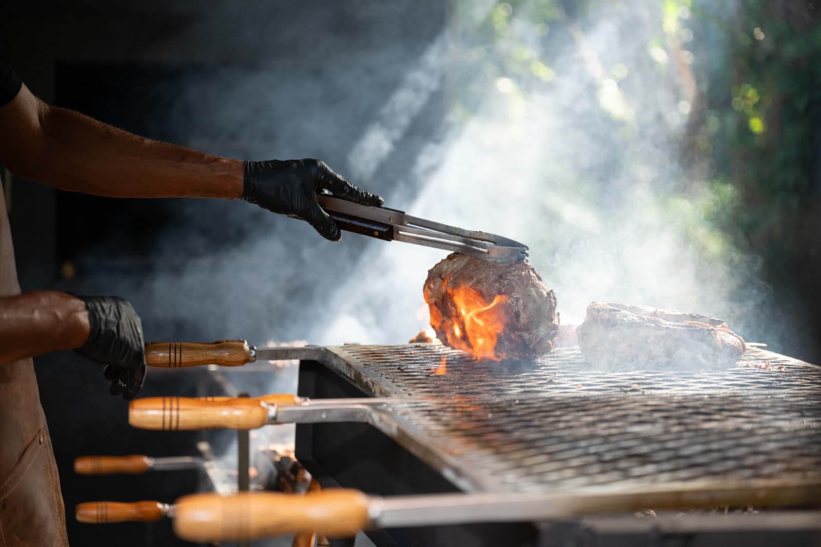 Carne na brasa sendo virada na grelha